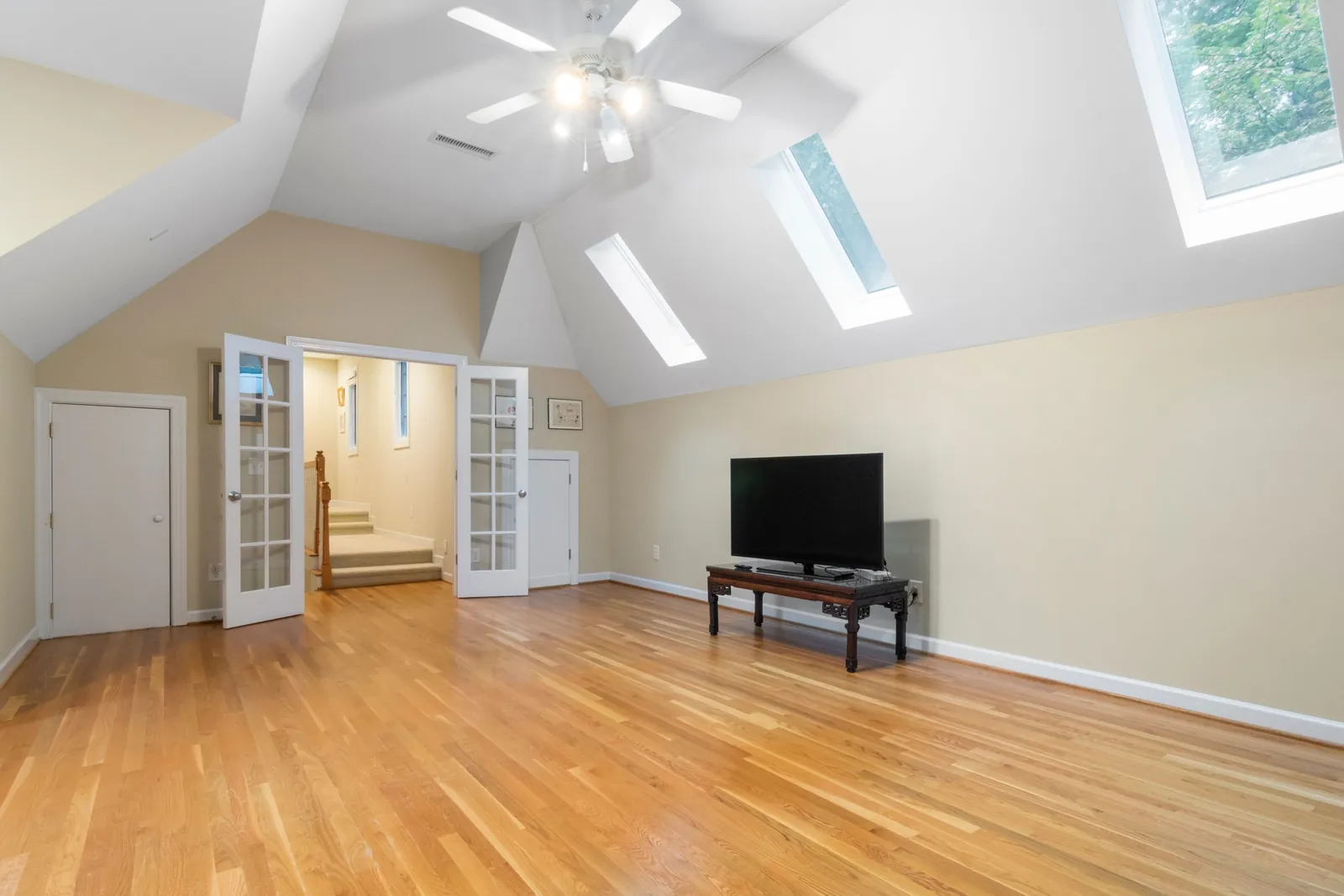 A finished attic room with skylights and a wood floor