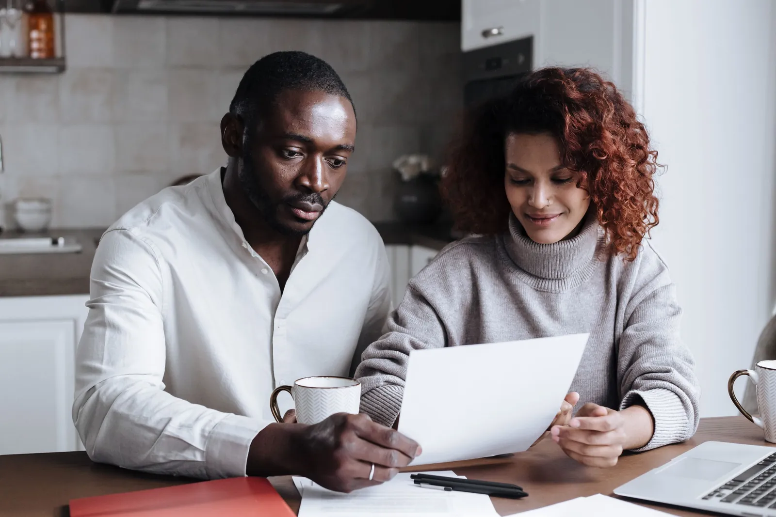 Two homeowners reading paperwork together at a kitchen table